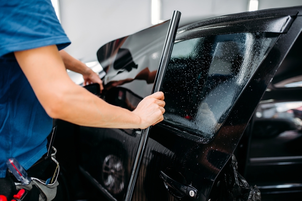 Technician applying window tint to a car